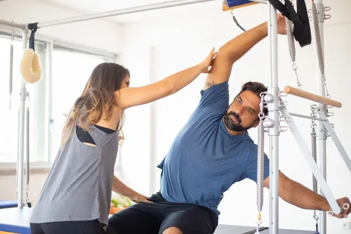 Fisioterapeuta guiando un estiramiento en la torre de pilates